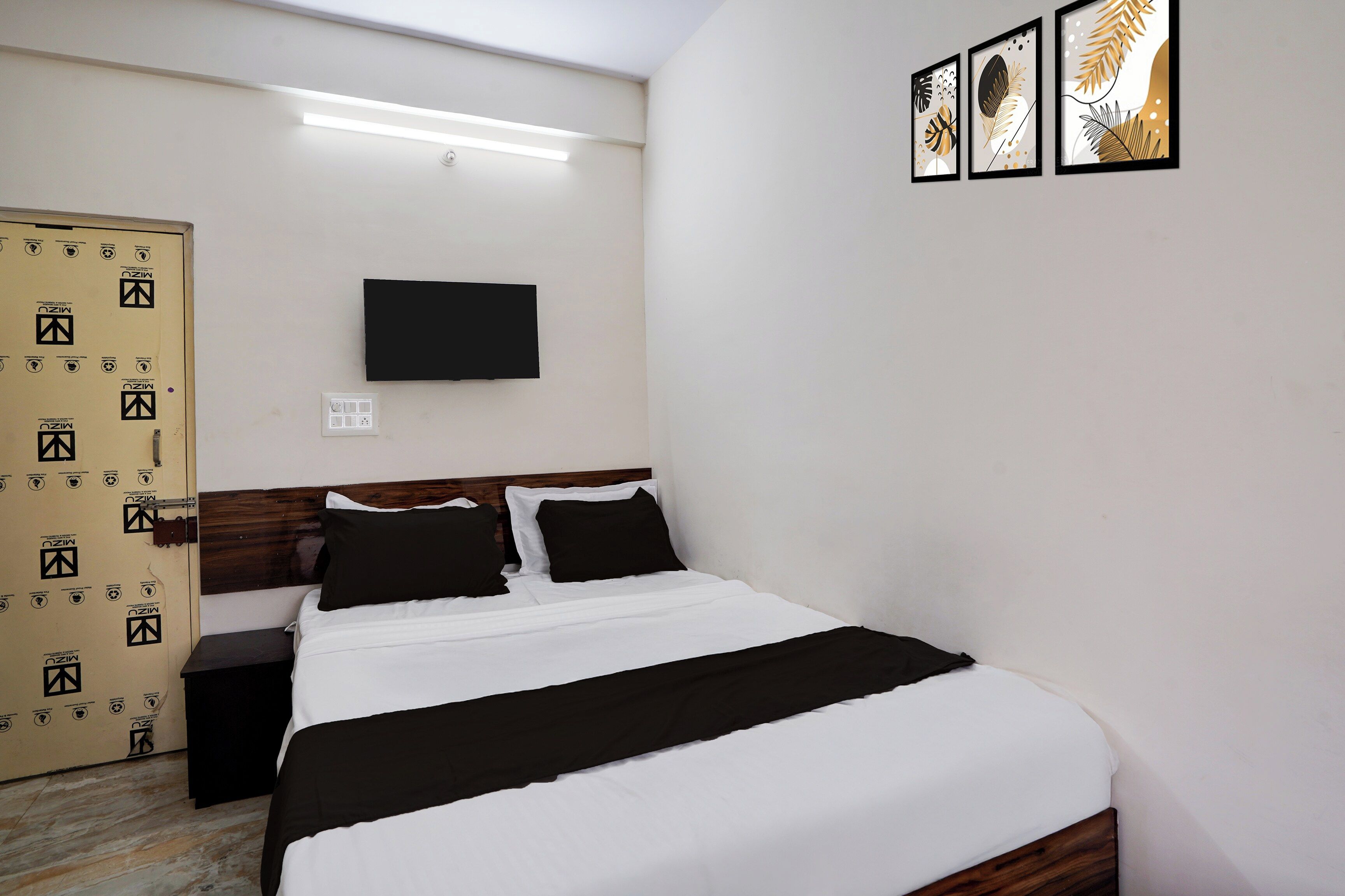 A hotel room with a bed, a TV mounted on the wall, and a door with a security lock.