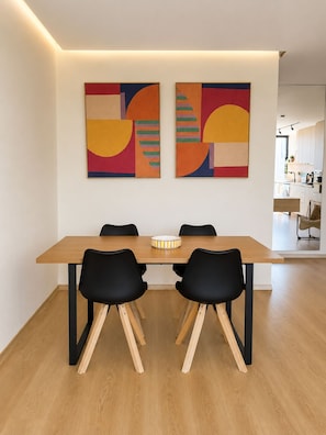 A dining area with a wooden table, black chairs, and two abstract paintings on the wall. - New Listing (Agadir)