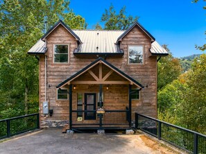 Eine zweistöckige Blockhütte mit Veranda, Metall-Dach und schwarzer Geländer.