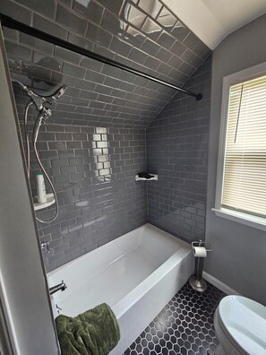 Un baño moderno con bañera, ducha e inodoro.