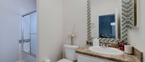 A bathroom with a toilet, sink, and shower area.