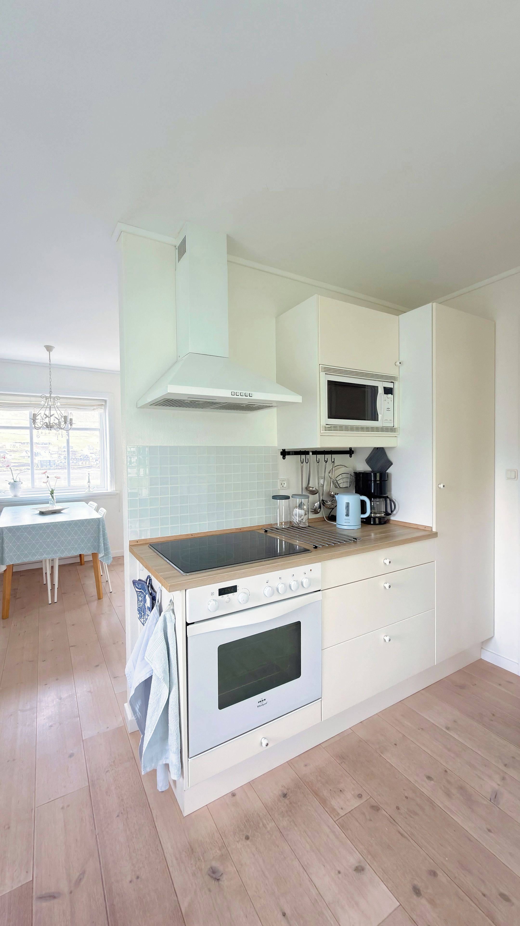 A modern kitchen with white cabinetry, a built-in oven, a microwave, and a window with a view.