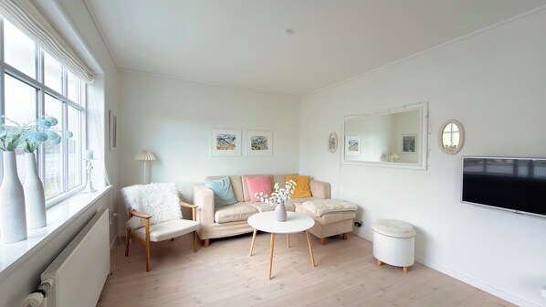 Un salon moderne avec un canapé, des fauteuils, une table basse et un téléviseur à écran plat.