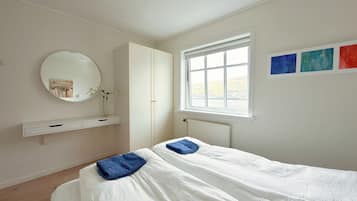 A bedroom with a bed, a wardrobe, a mirror, and a window.