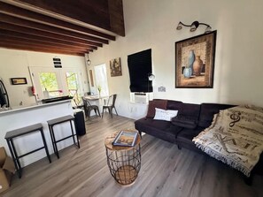 Uma sala de estar com sofá, mesa de centro e área de jantar com cadeiras.