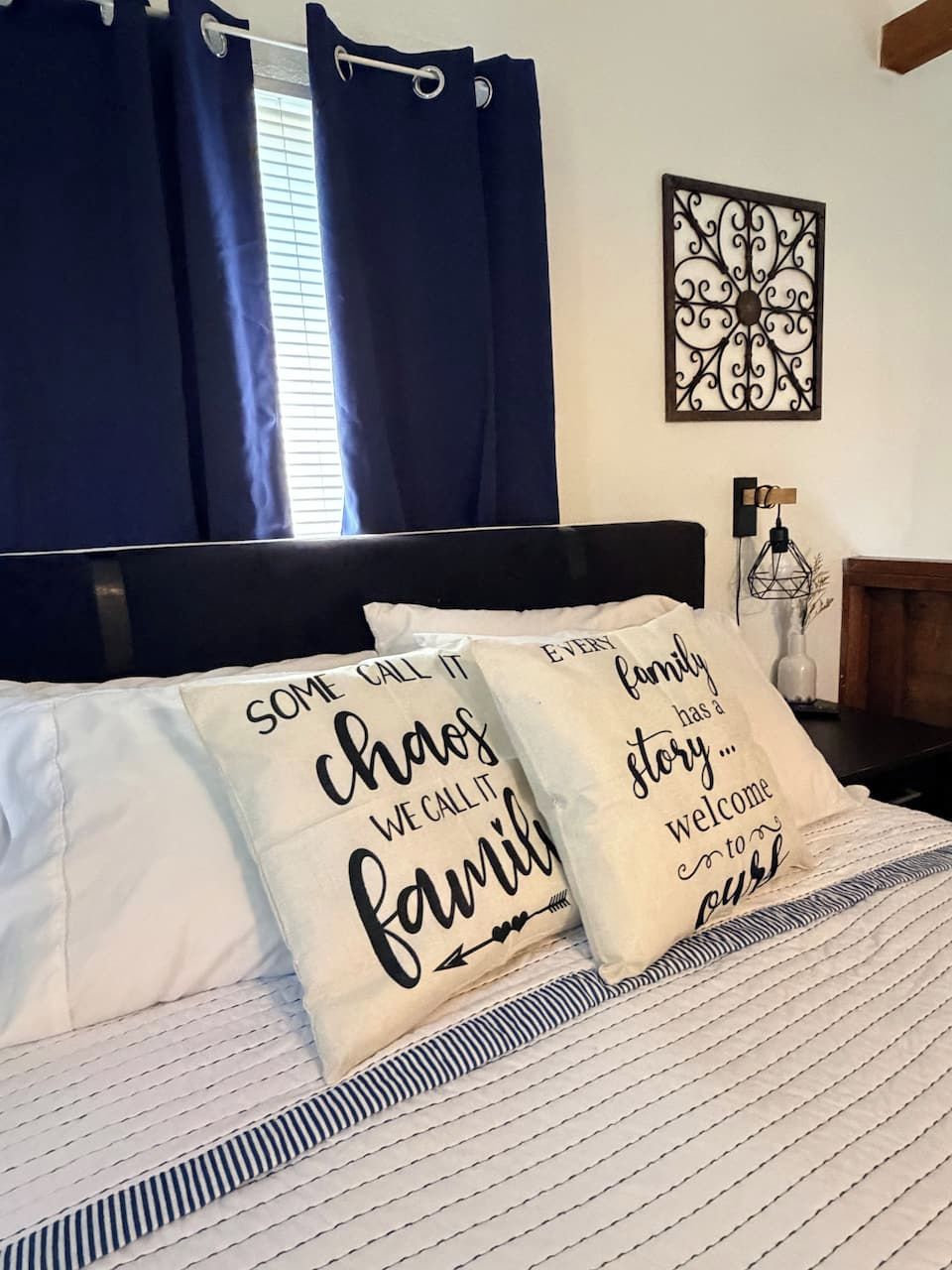 A bed with two pillows, a dark headboard, and a decorative wall piece.