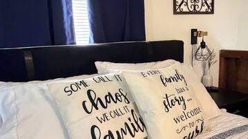 A bed with two pillows, a dark headboard, and a decorative wall piece.