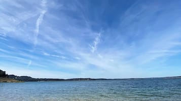 A clear sky over a calm body of water with visible rocks at the shore.