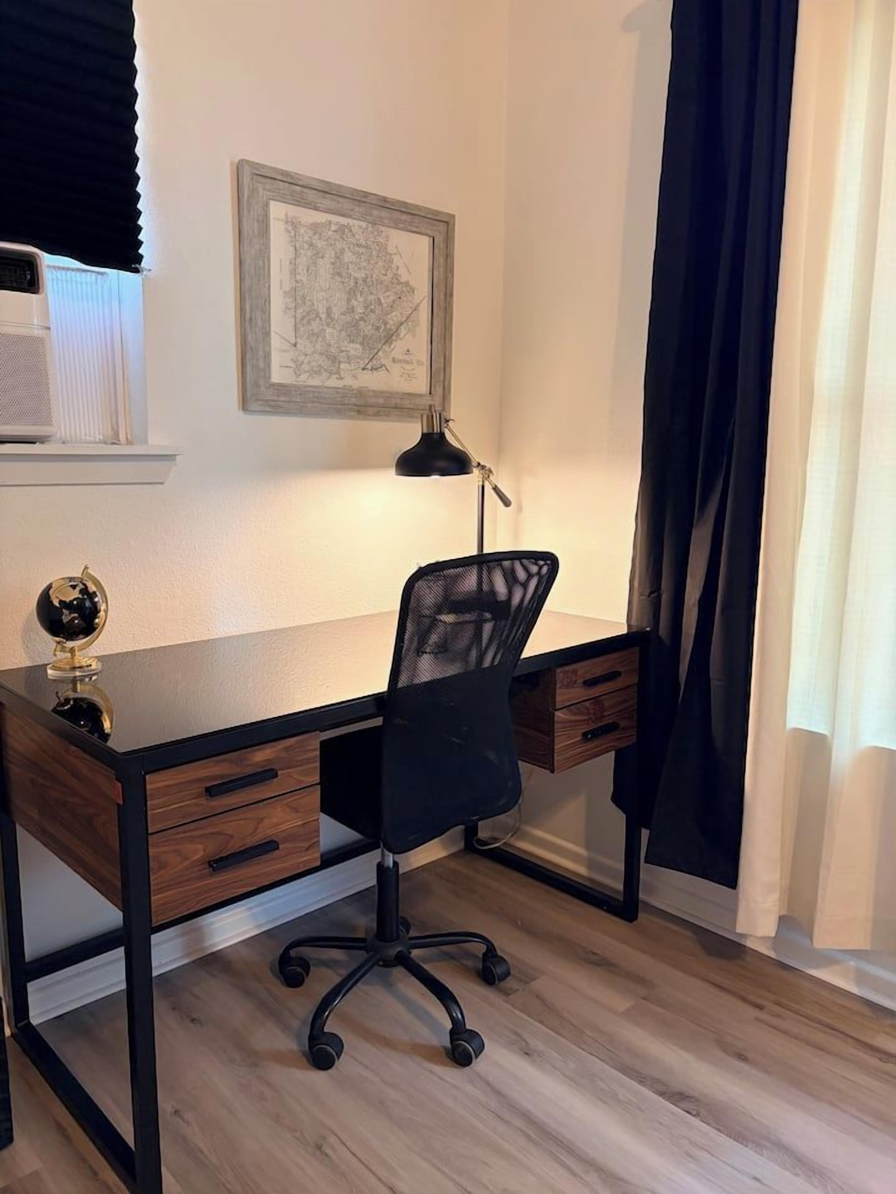 Un bureau moderne avec une chaise noire à dossier en maille, un globe terrestre et une carte encadrée accrochée au mur.