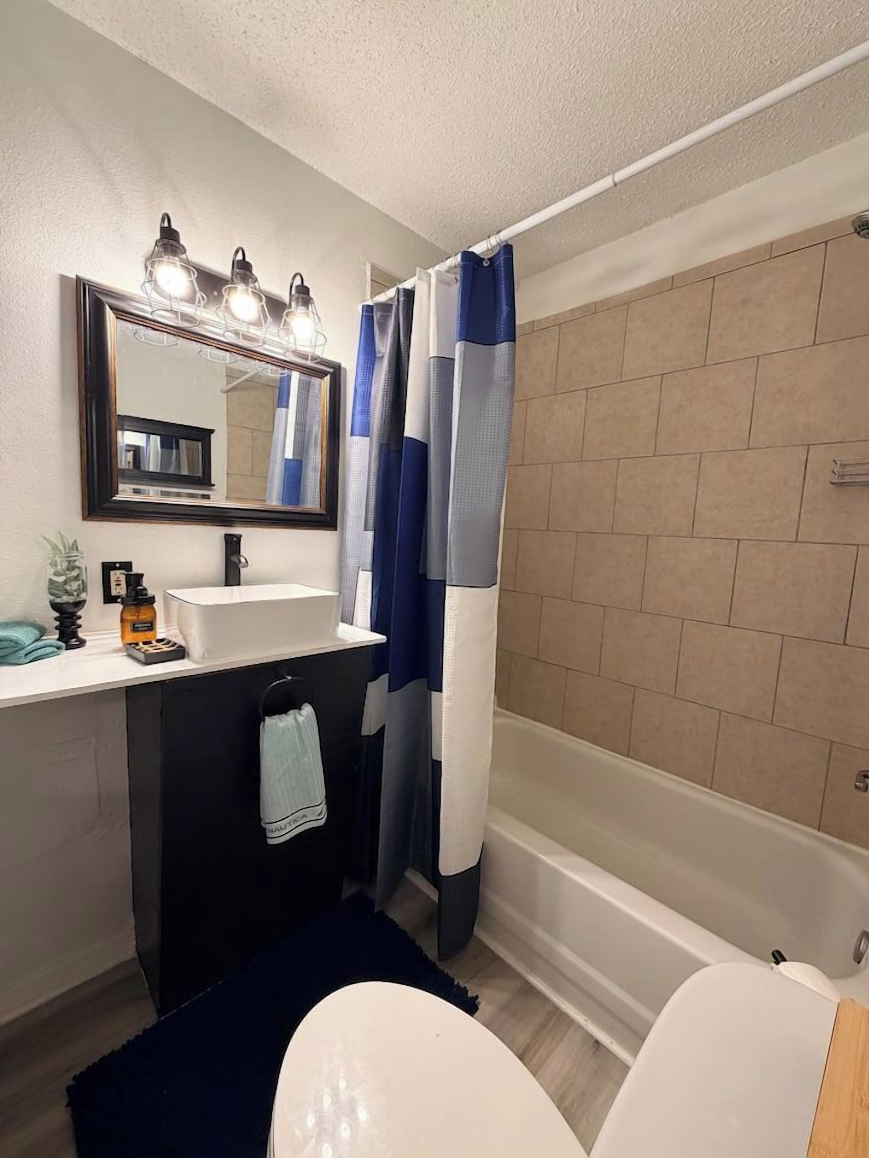 A bathroom with a white sink, mirror, and a bathtub.