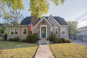 A single-story house with a stone facade, a front porch, and a flag. - Explore Scenic City Cozy Getaway Sleeps 8! (Chattanooga)