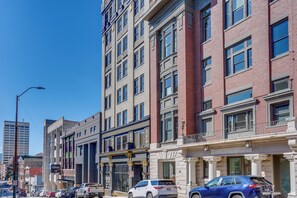 Un immeuble à plusieurs étages dont la façade combine des éléments en brique et des éléments modernes, avec de grandes fenêtres et un espace commercial bien visible, agrémenté d’une enseigne.