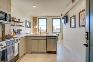 Una cocina moderna con una isla, horno empotrado y vistas de la ciudad a través de grandes ventanales.