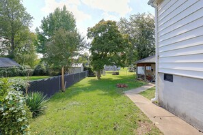 A residential backyard with a fenced area, a grassy lawn, and a house with a garage. - Studio Guest Suite Outside Baltimore (Parkville)