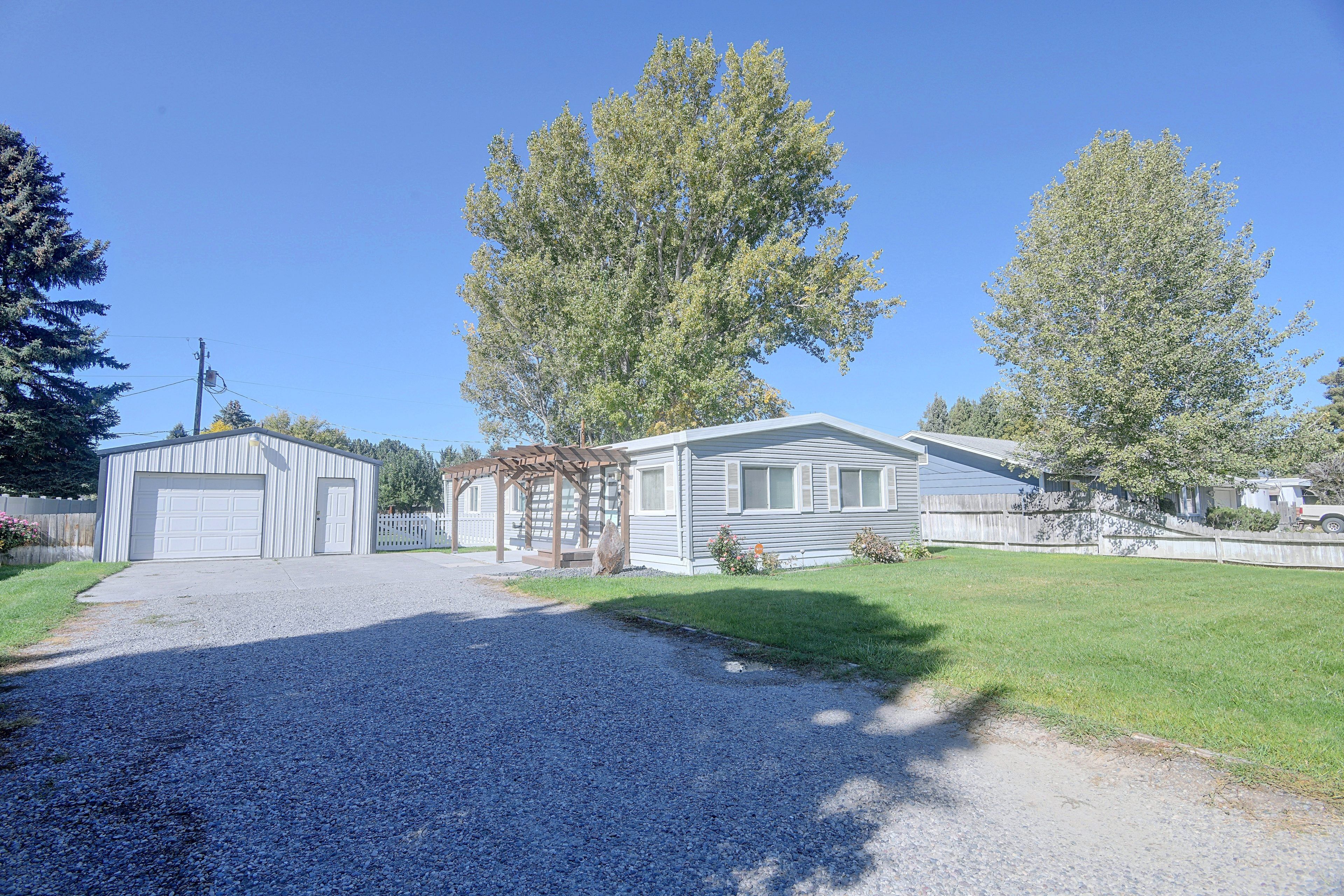 A residential property with a garage, a covered porch, and a grassy yard.