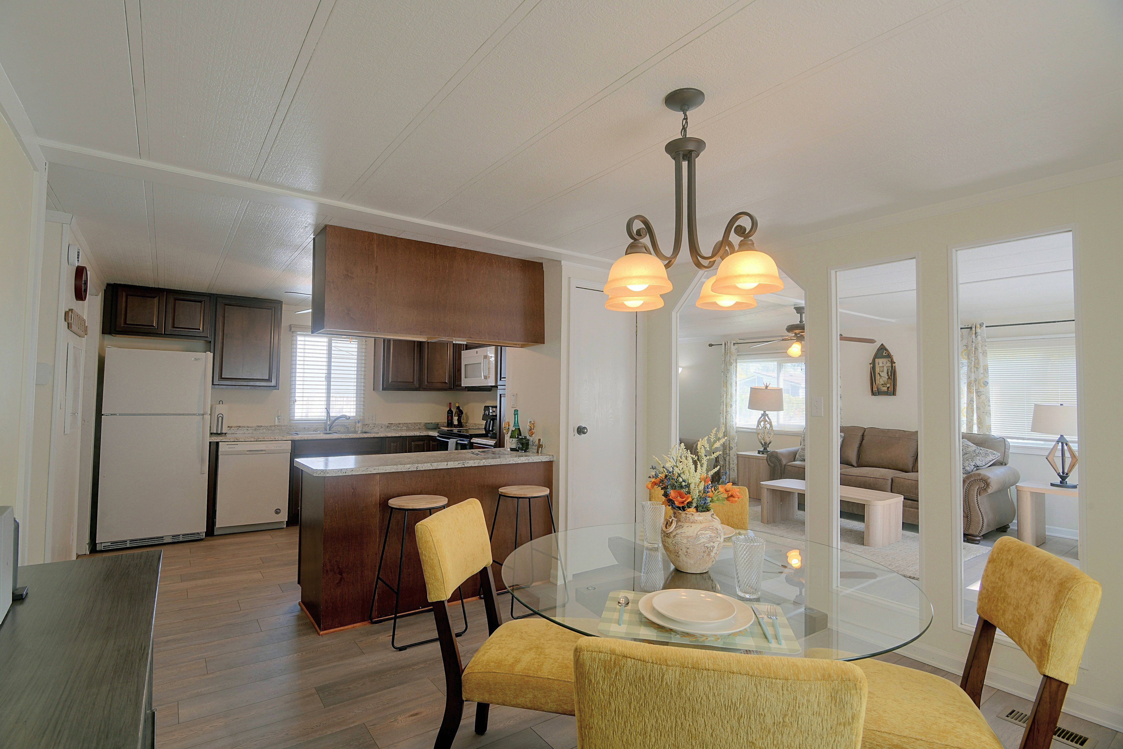 A modern kitchen with a central island, bar stools, and a dining table with chairs.