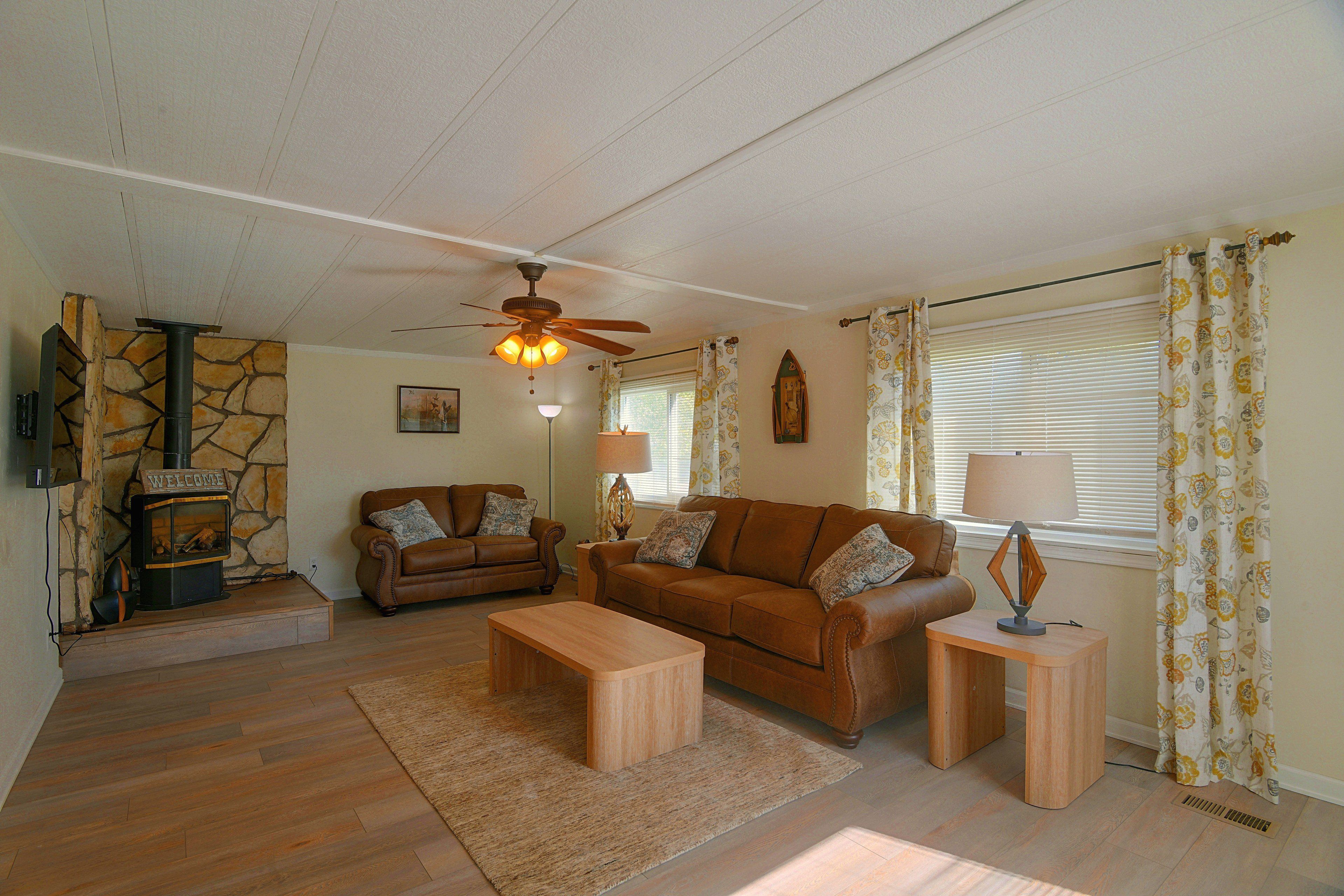 A living room with a stone fireplace, two sofas, a coffee table, and a ceiling fan.