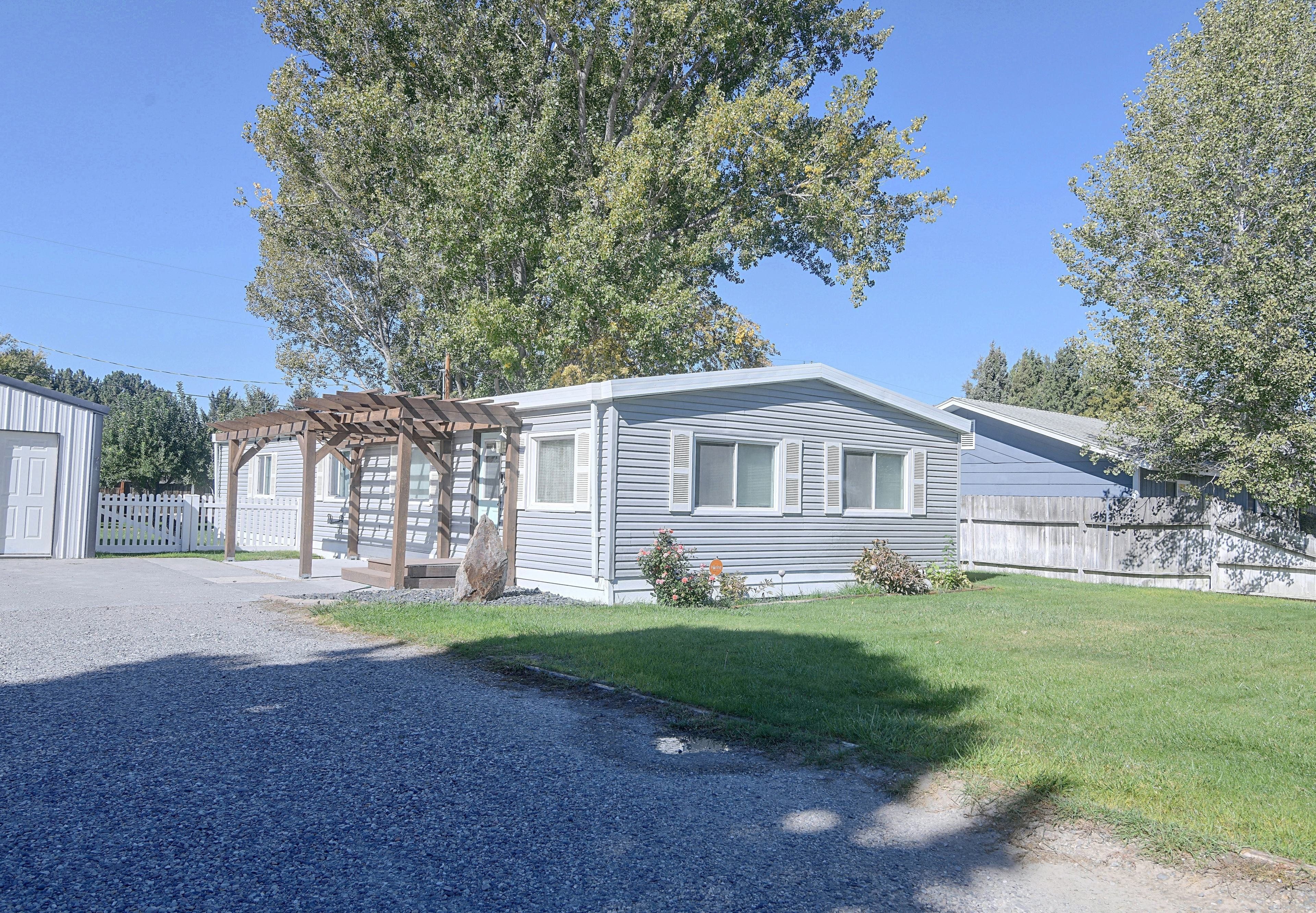 A single-story mobile home with a porch and a small garden area.