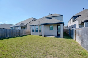 A residential property with a fenced backyard, a detached garage, and a main house with a gabled roof.