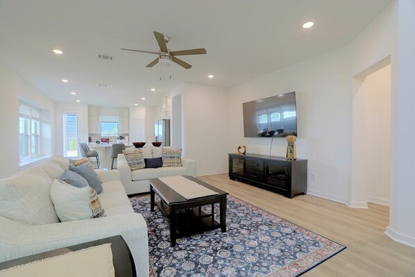 A modern living room with a sofa, coffee table, and a flat-screen TV mounted on the wall.