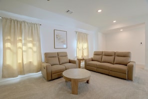 A living room with a beige sofa set, a round coffee table, and a small side table.