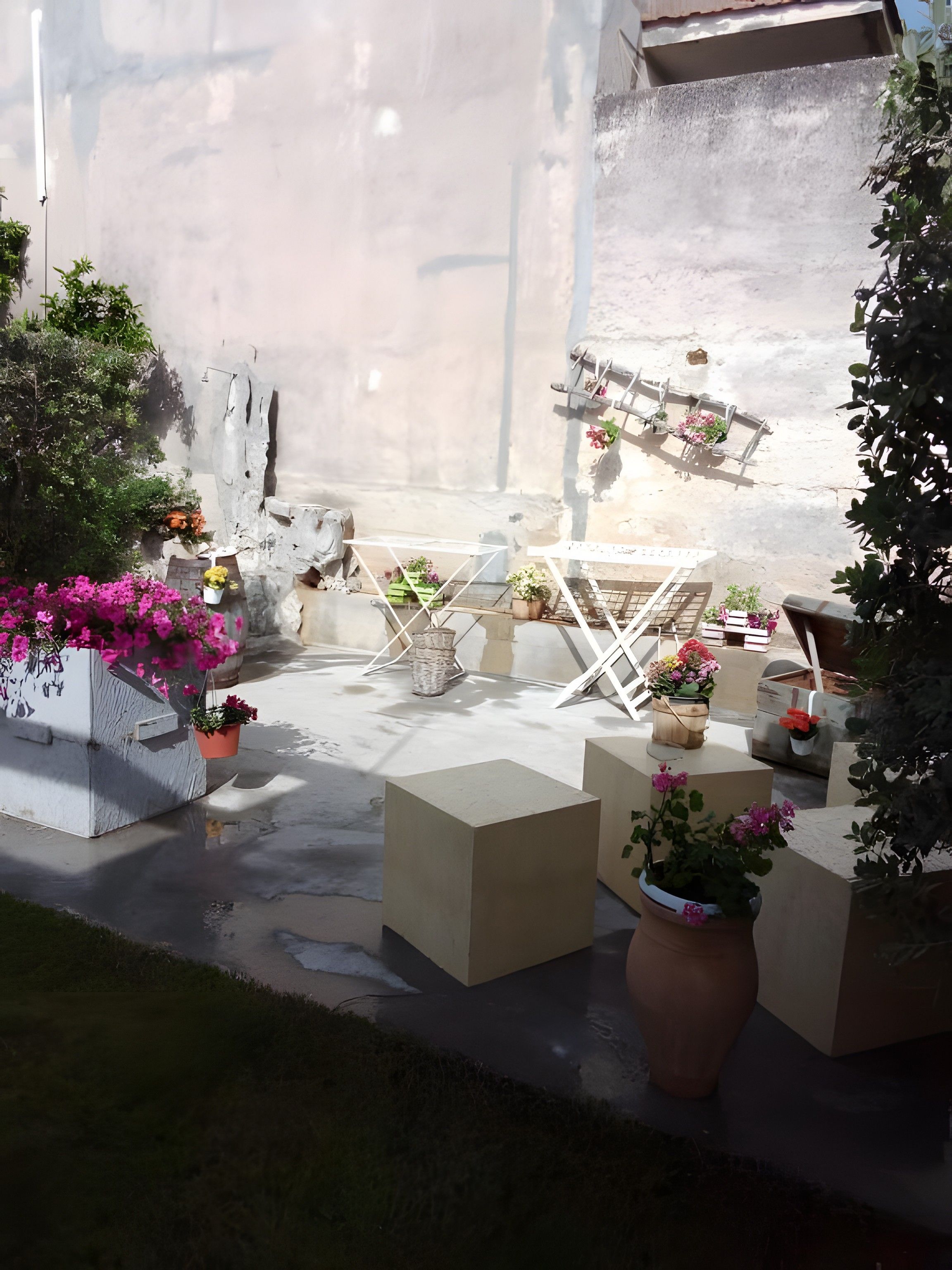En patio med udendørs møbler, krukker med planter og en støbt gulv.