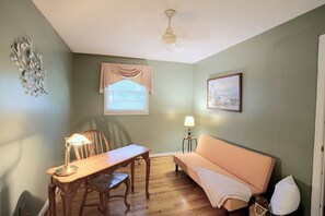 A room with a wooden dining table, a chair, a sofa, a lamp, a window with curtains, a ceiling fan, and a framed picture on the wall. - Small Town Charm: Historic Eastover Home (Eastover)