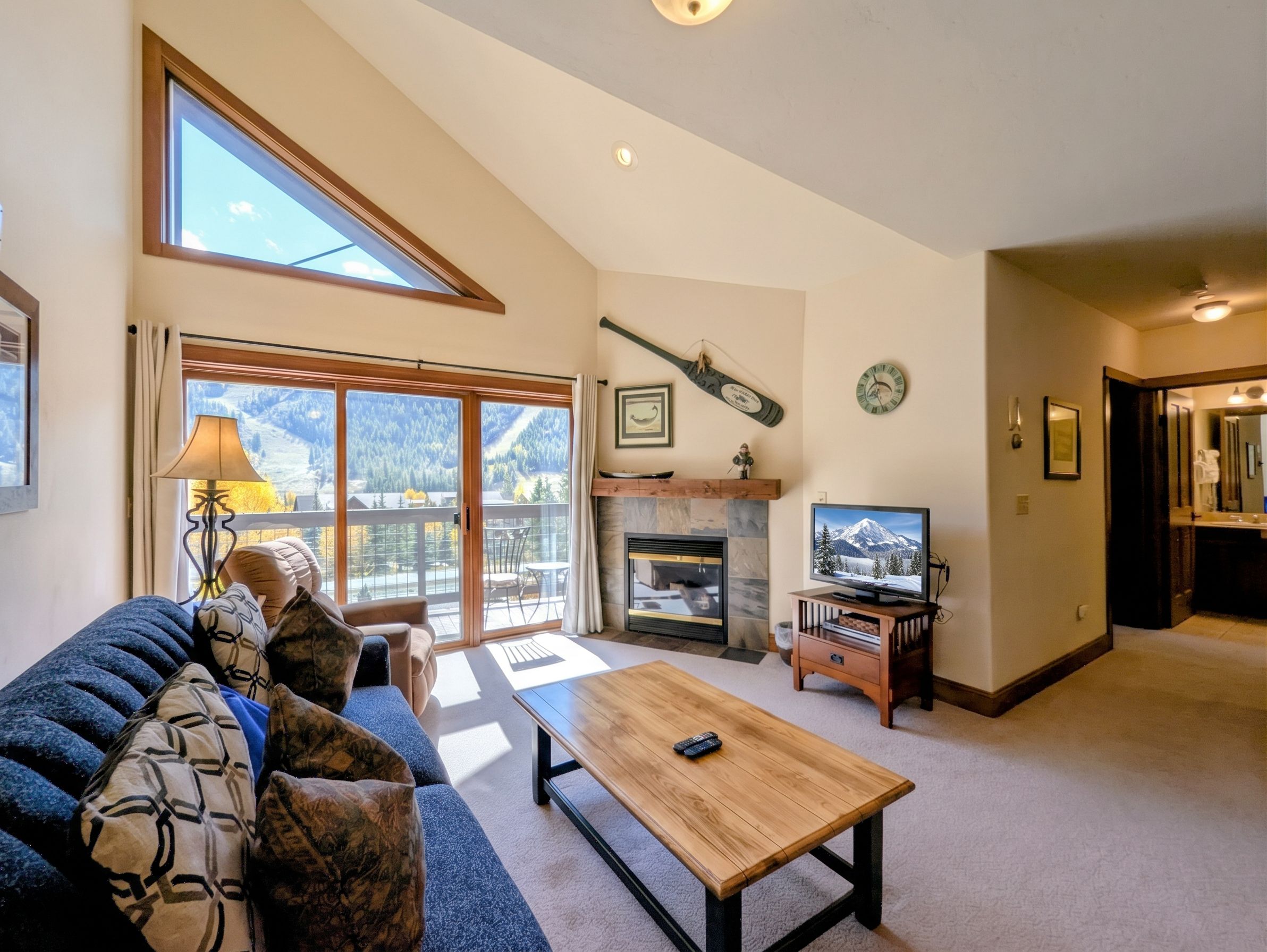 A spacious living room with a large window, a fireplace, a television, and a sofa.
