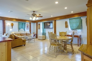 A spacious living room with a sofa, a dining table with chairs, a ceiling fan, and a television on the wall. - Your Home Base in Southern Louisiana (Buras-Triumph)