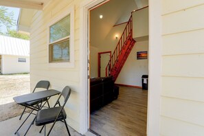 A room with a wooden floor, a red staircase, and a table with chairs.