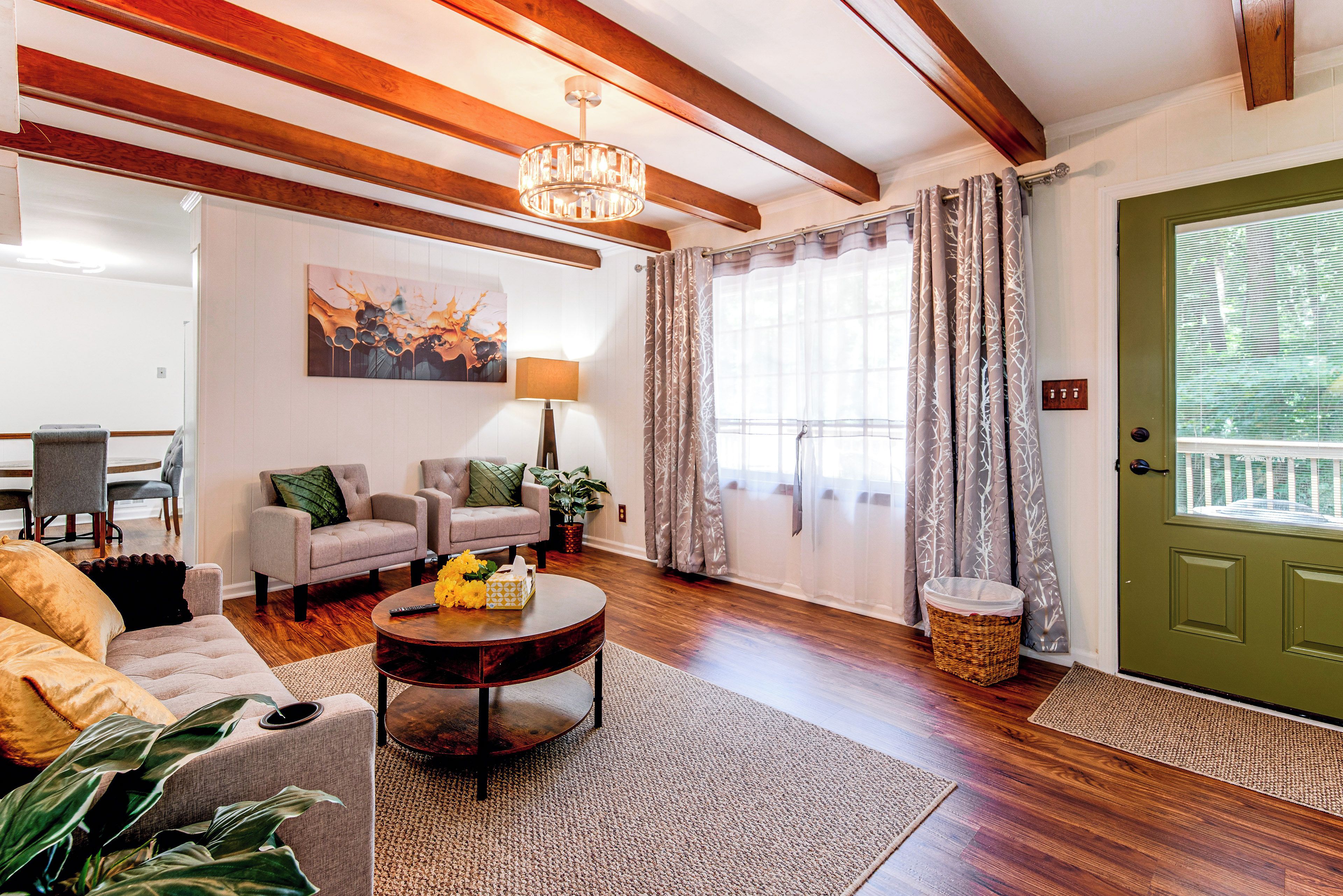 A living room with a fireplace, a chandelier, and a dining area with a table and chairs.