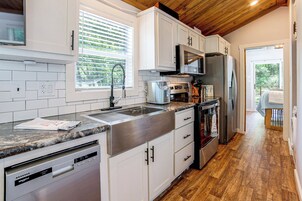 Una cocina moderna con armarios blancos, electrodomésticos de acero inoxidable y techo de madera.