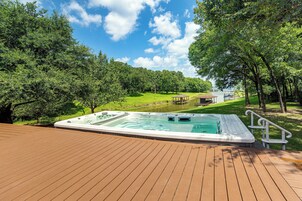 Un jacuzzi en una terraza de madera con vistas a un lago y árboles.