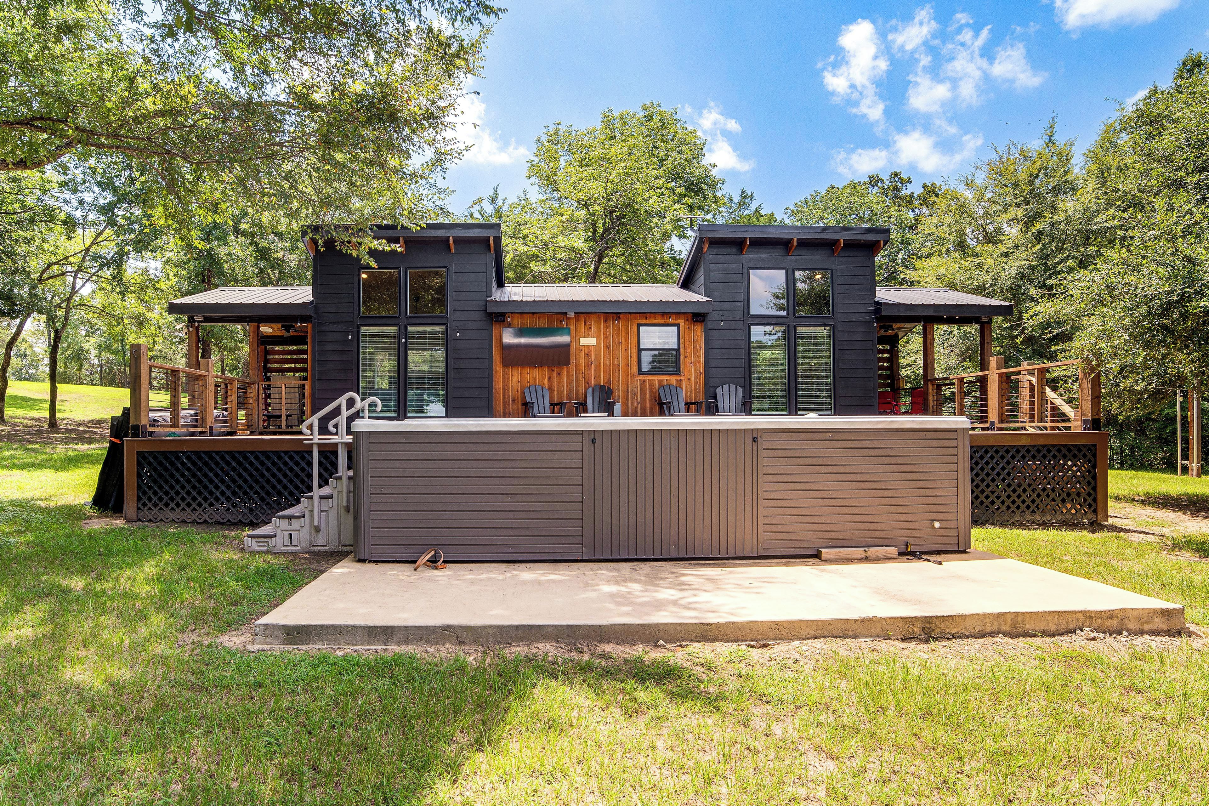 A modern two-story cabin with a deck and outdoor seating area.