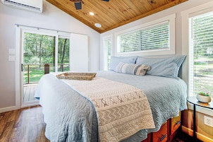 Un dormitorio con una cama grande, techo de madera y vistas al exterior con vegetación.