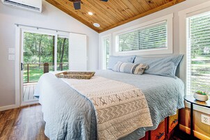 Un dormitorio con una cama grande, techo de madera y vistas al exterior con vegetación.