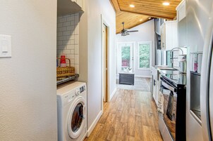 Un área de lavandería con lavadora, secadora y ventilador de techo.