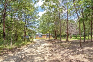 Una cabana envoltada d'arbres, amb un camí de grava que hi convergeix.