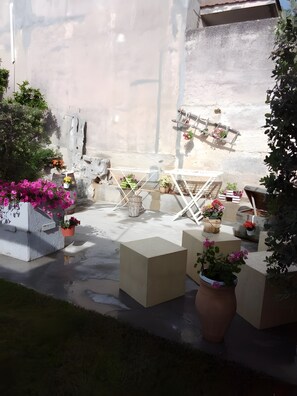 En patio med udendørs møbler, krukker med planter og en støbt gulv.
