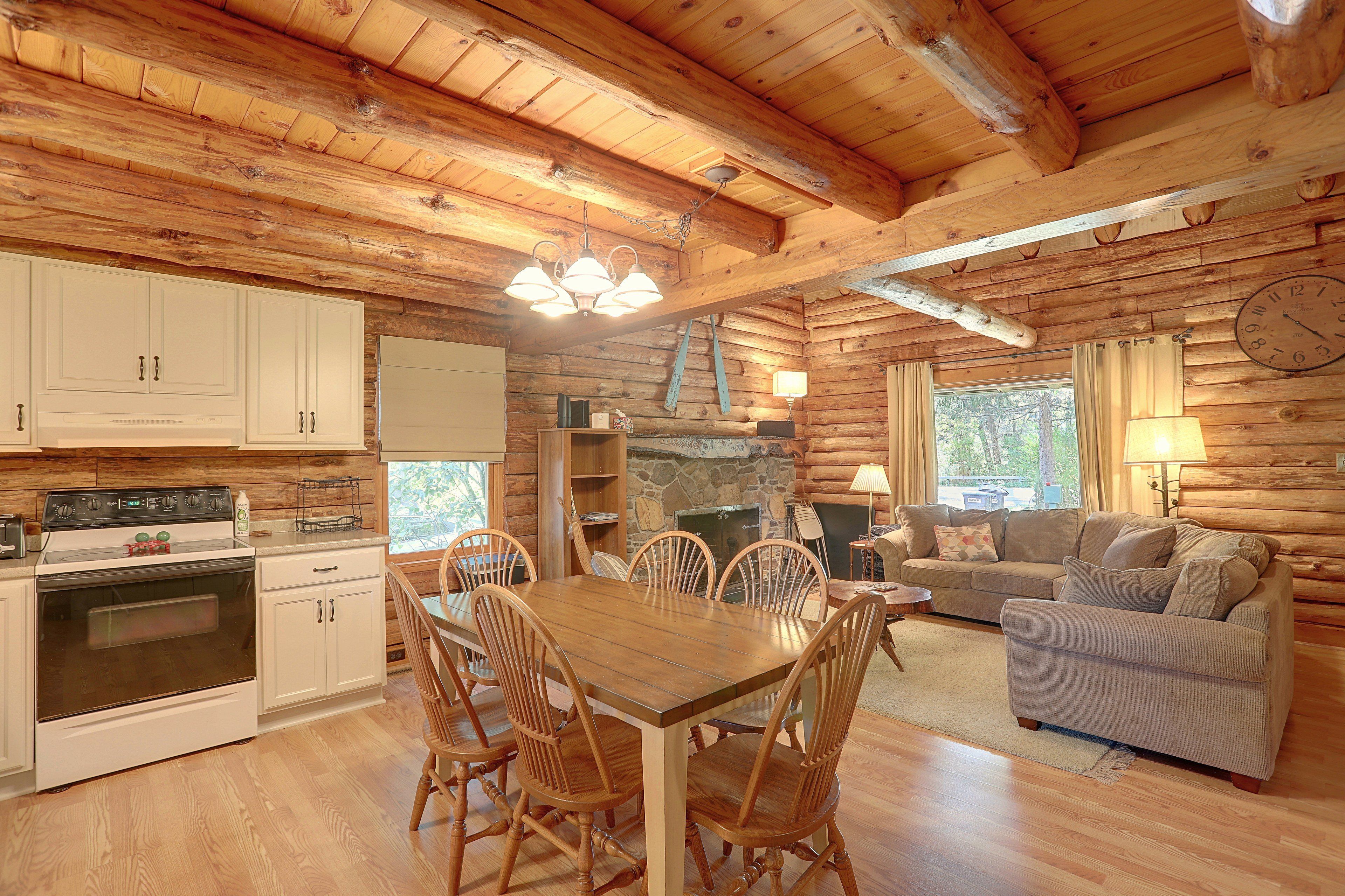 A log cabin interior with a dining area, kitchen, and living space.