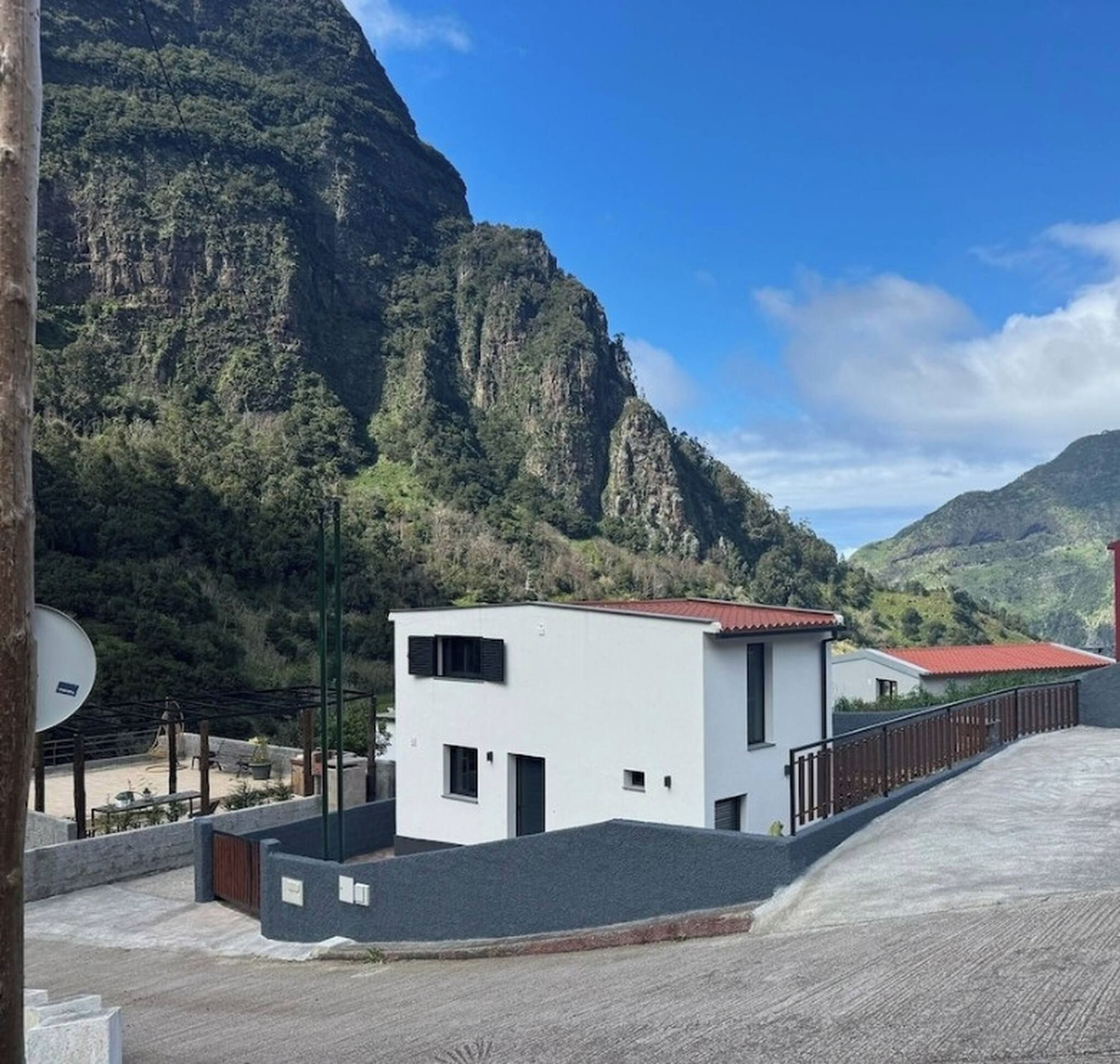 A modern building with a flat roof, a small balcony, and a view of a mountainous landscape.