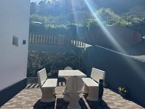 Eine Außenpatio mit Tisch und Stühlen, einer Steinmauer und Blick auf einen Garten.