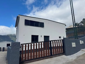 A modern two-story building with a white exterior, black shutters, and a black metal gate. - Little Hideaway - São Vicente (São Vicente)
