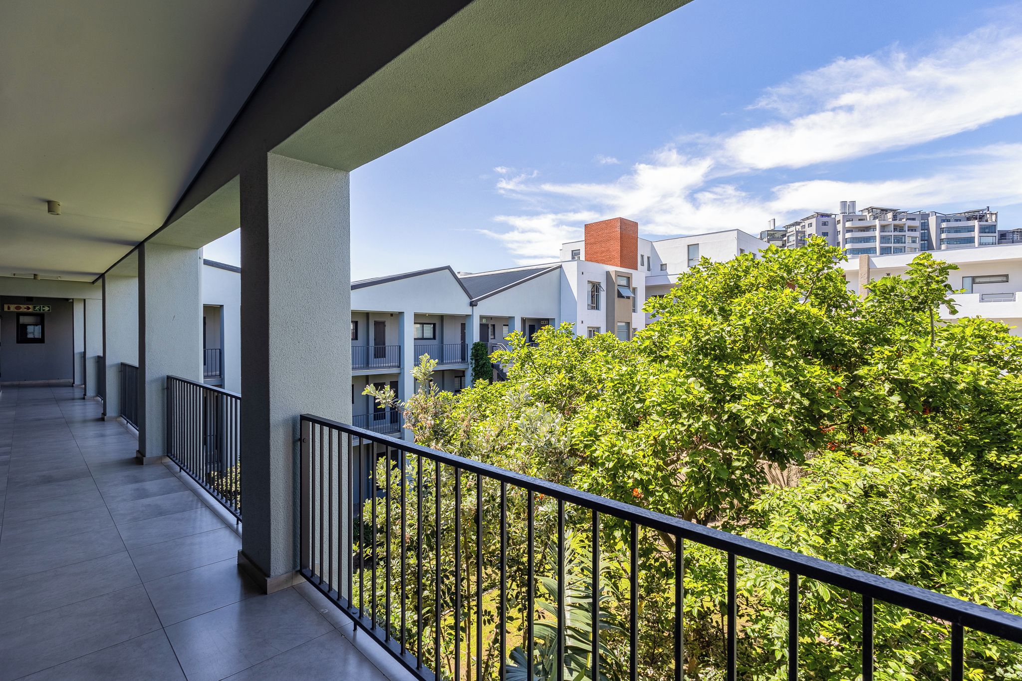 A covered outdoor balcony with a view of residential buildings and greenery.
