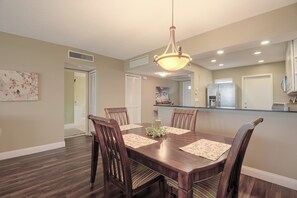 A dining area with a wooden table, chairs, a chandelier, and a kitchen in the background. - Stunning Golf Course Views! Sarasota Extended Stay (Sarasota)