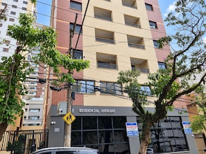 A multi-story residential building with balconies, a pedestrian crossing sign, and commercial signage. - New Listing (São Paulo)