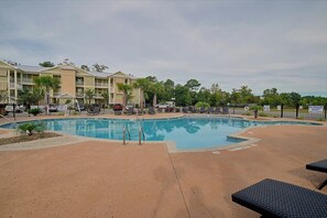 A swimming pool with lounge chairs and a building in the background. - Stunning Murrells Inlet Townhome Near Marshwalk (Murrells Inlet)
