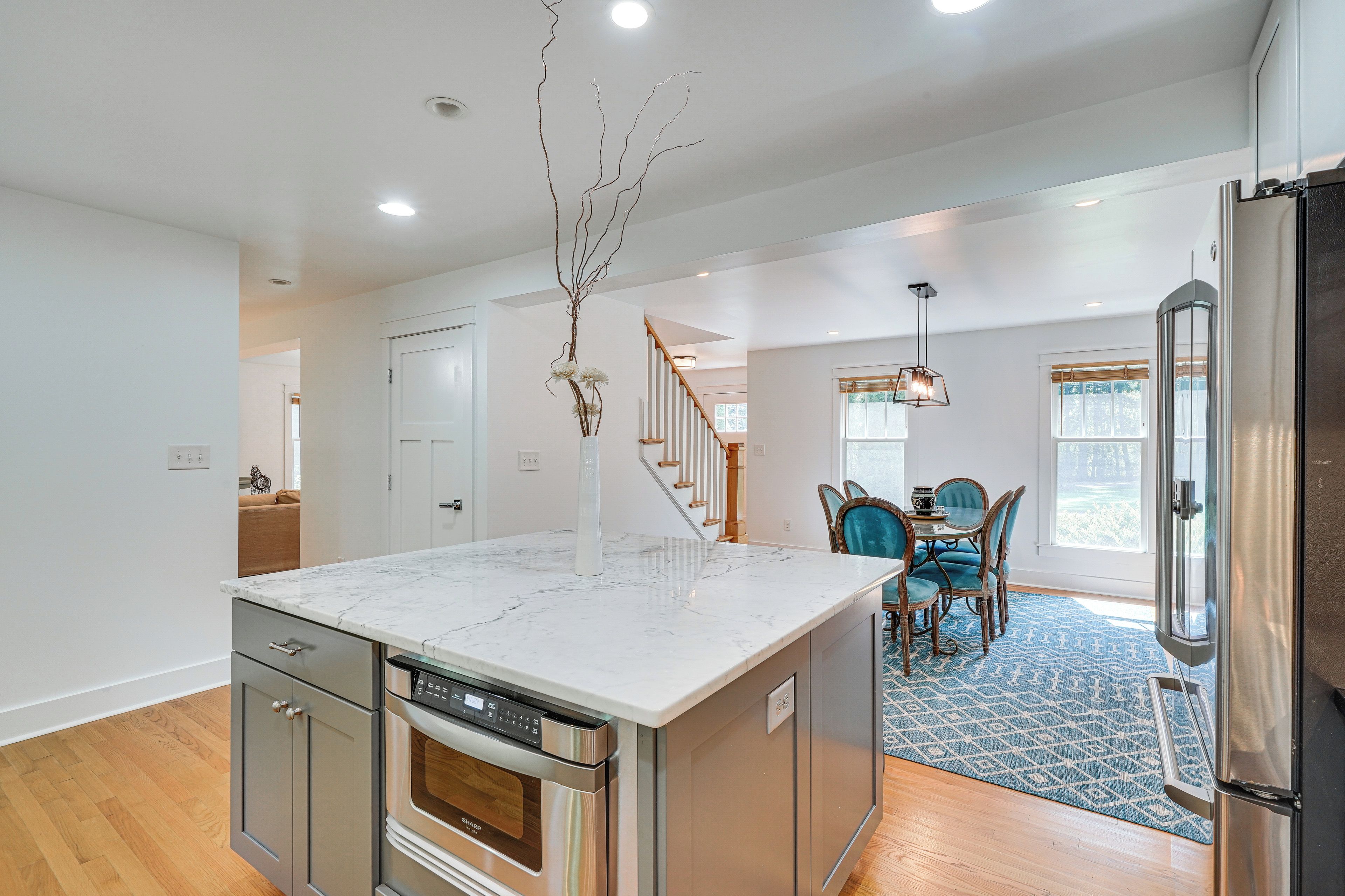 A modern kitchen with a central island, stainless steel appliances, and a dining area with blue chairs.