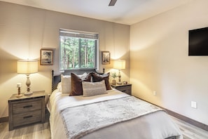 A bedroom with a bed, two bedside tables, a window with a view of trees, and a wall-mounted TV. - Golfers Oasis! Ponderosa Pine Retreat in Show Low (Show Low)