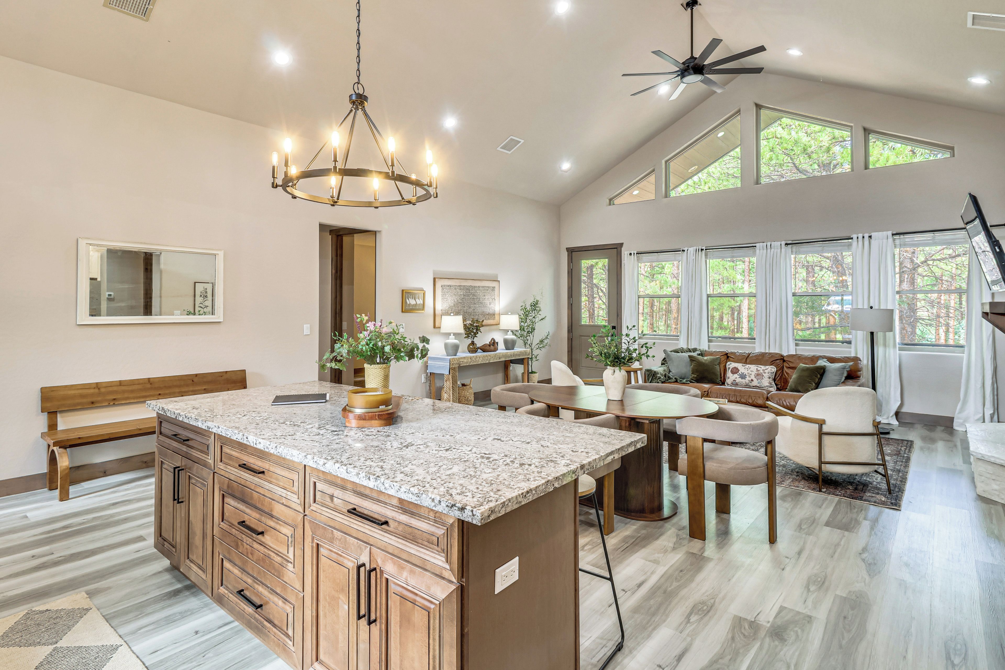 A spacious kitchen with a large island, wooden cabinets, and a chandelier.
